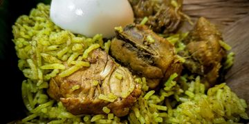 Seeraga samba biriyani with chicken pieces and a boiled egg on a leaf plate.