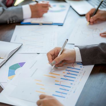 Business professionals analyzing summary reports with charts and graphs during a meeting.
