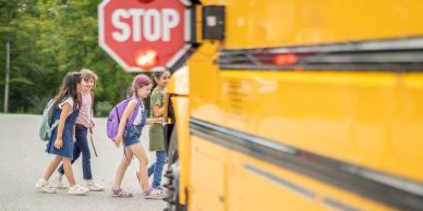 Children boarding a yellow school bus near a stop sign.