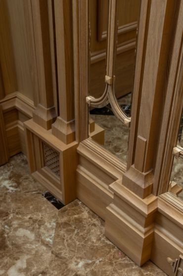 Elegant wooden molding with mirrored panels on marble floor.