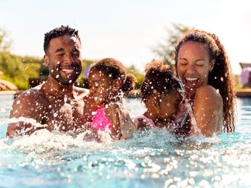 A joyful family splashing and laughing together in a pool.