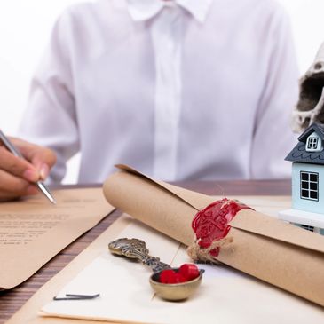 Person signing legal documents with symbolic items on the desk.