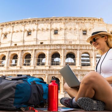 Woman working on laptop outside the Colosseum in Rome.