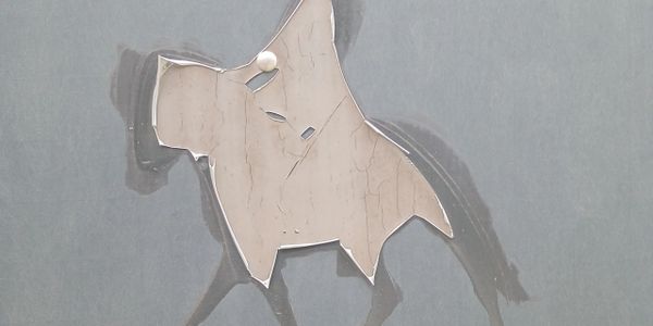 Worn-out dog silhouette sticker on a grey surface.