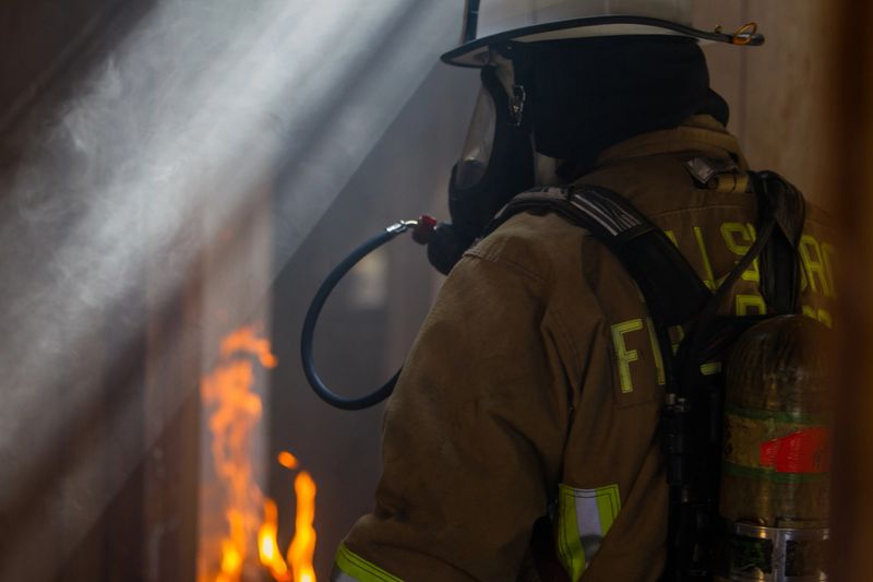 Firefighter wearing bunker gear, helmet, and mask. This is inside a bun house, a controlled burn, for training purposes.