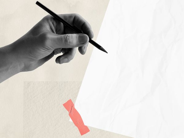 Hand holding a pencil poised above a blank sheet of paper taped to a surface.