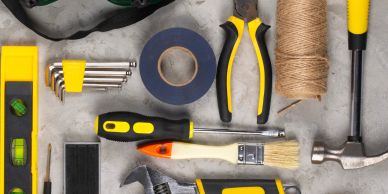 Assorted yellow and black tools and tape arranged on a surface.