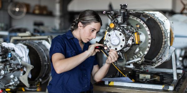 Woman repairing an engine in a workshop.
