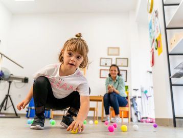 Young girl playing with colorful balls indoors.