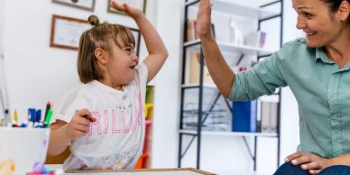Child and woman giving a high five during a drawing activity.