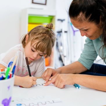 A young girl and woman focused on drawing together at a table.