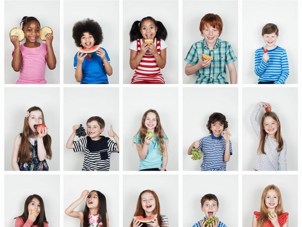 Children happily eating various fruits against a white background.