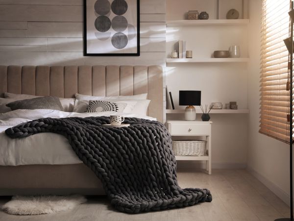 Cozy bedroom with a chunky knit blanket and soft lighting.