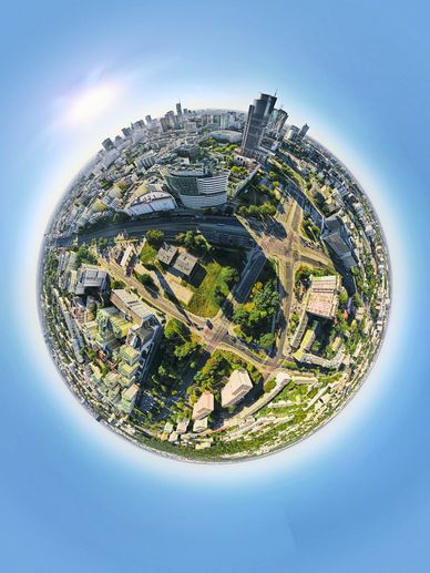 A tiny planet view of an urban cityscape with buildings and roads under a blue sky.