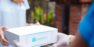 Person delivering a pharmacy package in protective gloves.
