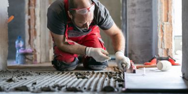 Worker installing floor tiles with precision tools.