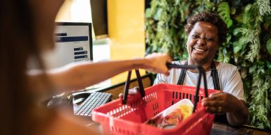 Smiling cashier handing basket back to customer.