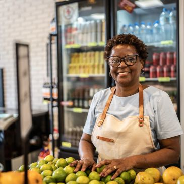 Femme souriante vendant des fruits au marché.