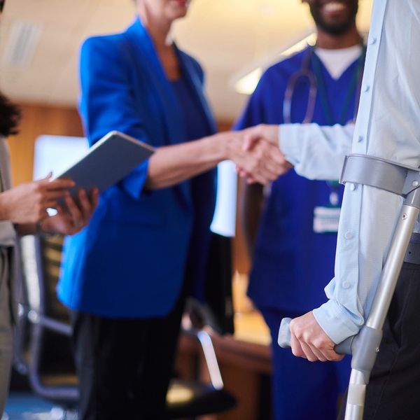 Person with crutches shaking hands with a healthcare professional.