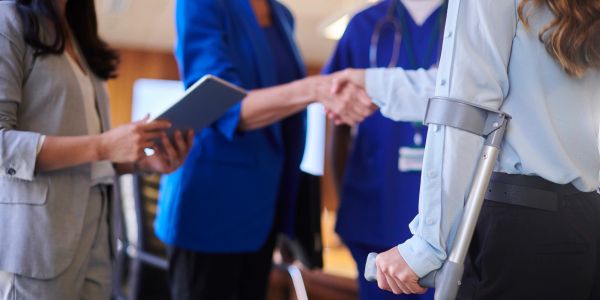 Person with crutches shaking hands with a medical professional.