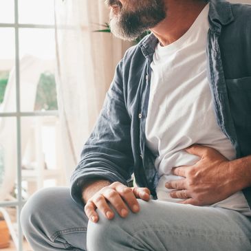 Middle aged man with grey beard holding painful stomach while feeling irritable bowel symptoms