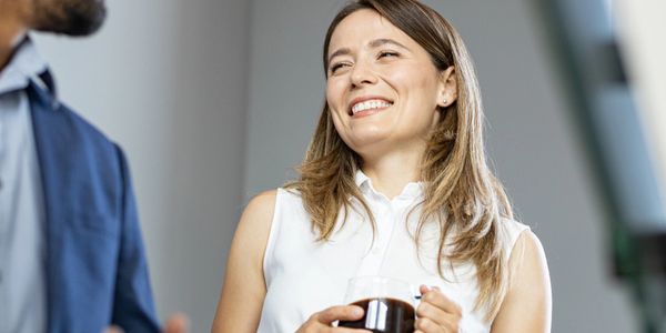 Two colleagues sharing a light moment over coffee at work.