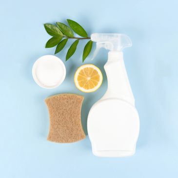 Cleaning supplies with lemon and leaves on blue background.