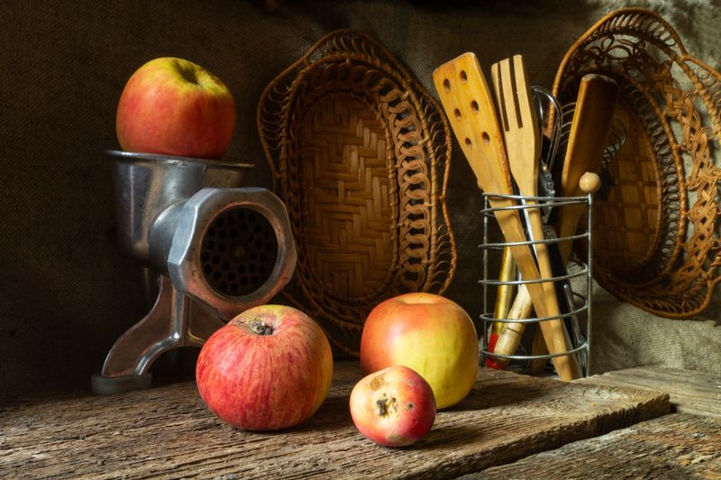 Ripe apples with cooking utensils. Fruit with a meat grinder on an old wooden table