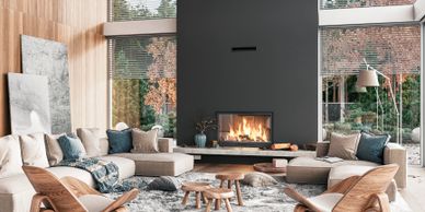 Modern living room with large windows, cozy fireplace, and elegant wooden furniture.