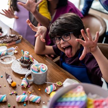 Joyful child making a funny face while decorating sweets at a party.