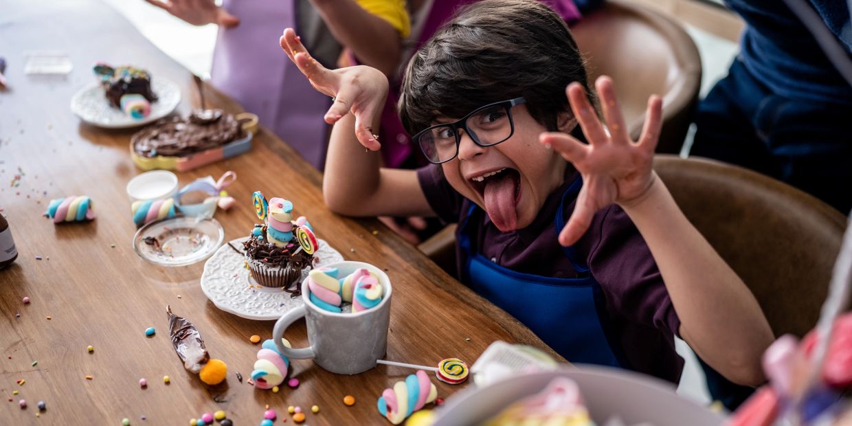 Child making a funny face at a candy-decorated table.