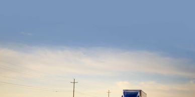 Truck driving on an empty road during sunset with power lines.