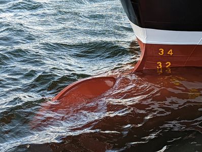 Close-up of a ship's bow with draft markings partially submerged in water.