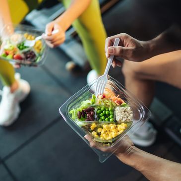 Two people eating healthy salads from plastic containers.