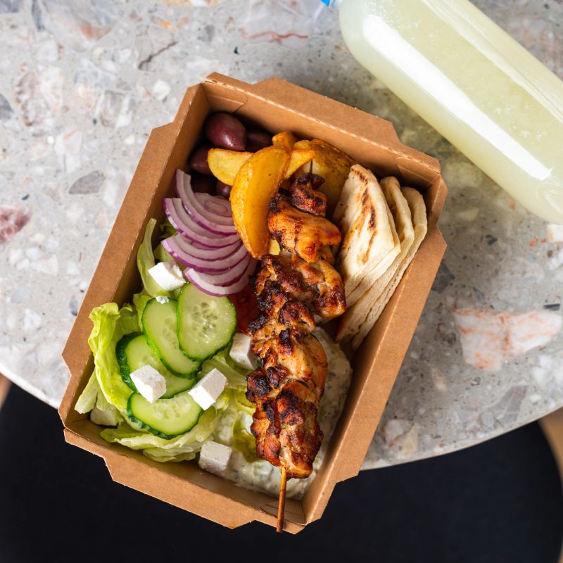 Fast food delivery.Greek souvlaki,salad and gyros take away menu from fastfood restaurant served in recyclable paper plates on table.