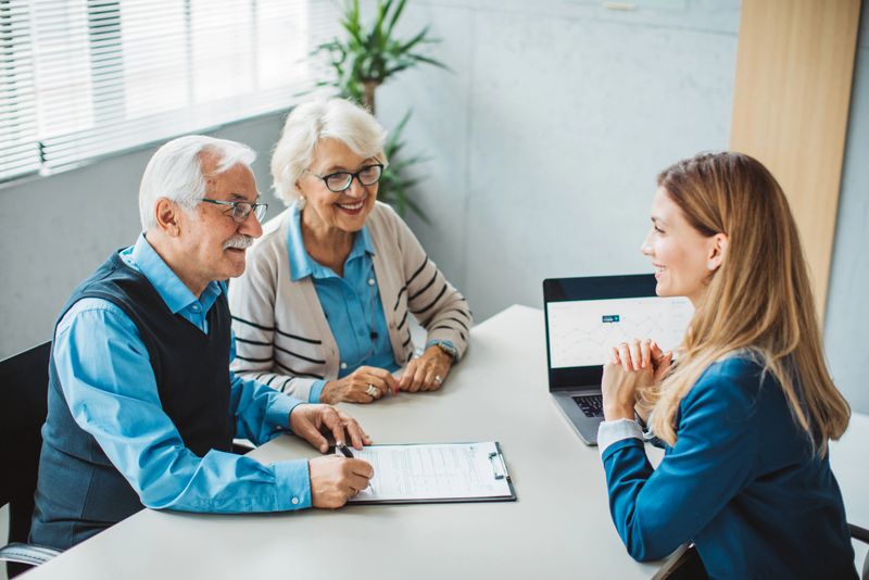 Senior couple talking with female financial or real estate advisor at her office.