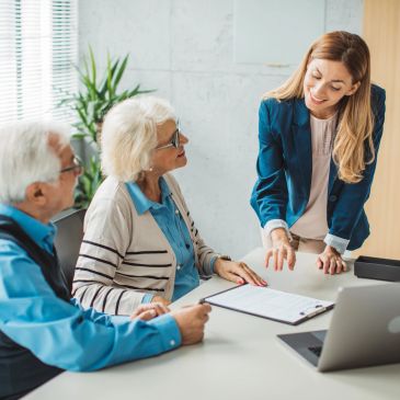 Young woman helping elderly couple with paperwork.