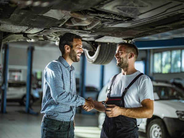 Auto technician greeting customer at repair shop