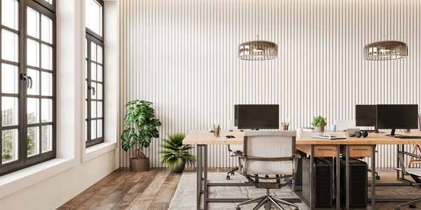 Modern office workspace with desks and large windows.