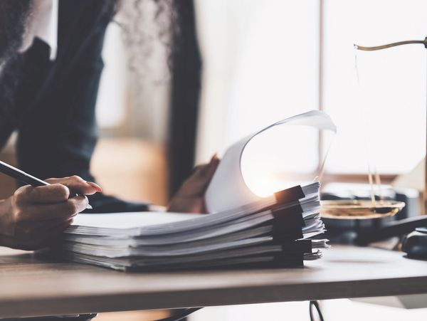 Person reviewing documents with legal symbols on the desk.