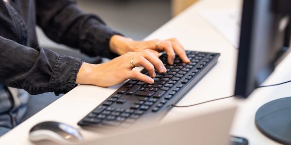 Person typing on a keyboard at a desk.