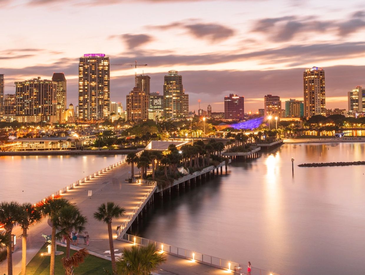 City skyline and waterfront at sunset with lights on.