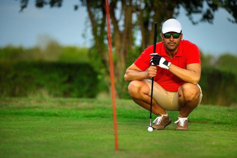 Closeup front view of a young man at a golf course planning his next shot.