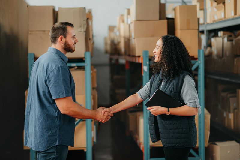 Shipping, supply chain and delivery workers with handshake for partnership, support and thank you in a warehouse. Box logistics or stock factory employee with teamwork, collaboration business meeting