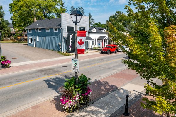 Street view in Kleinburg with Canadian flag and red vehicle.