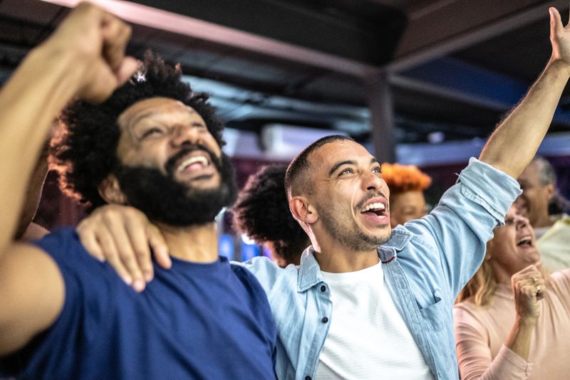 Sports fans watching a match and celebrating at a bar