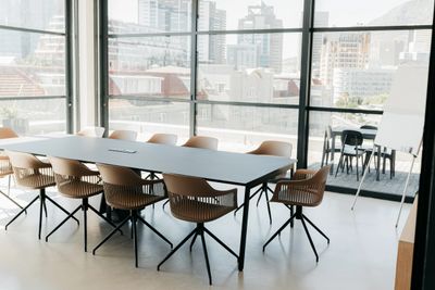 Modern conference room with a long table and chairs near large windows.