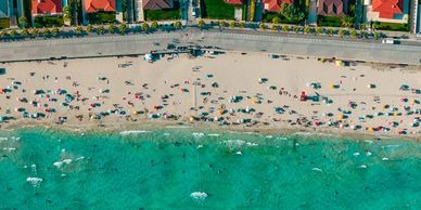 Aerial view of a beach with turquoise water and houses nearby.