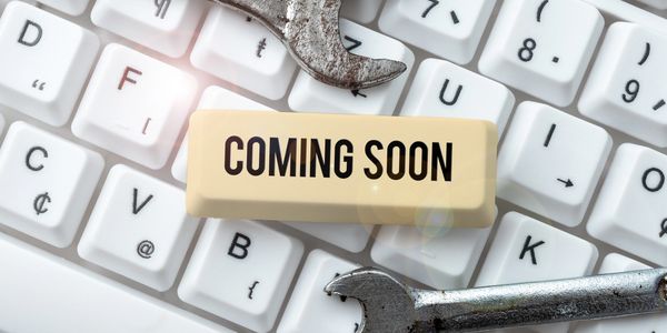 A keyboard with a "Coming Soon" key and two rusty wrenches.