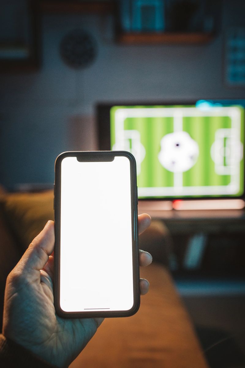 Close up of men's hand using smart phone for sports betting .
